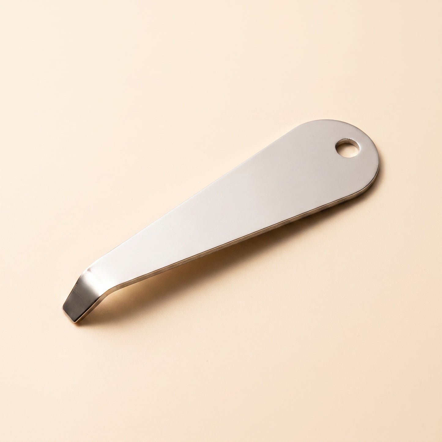 Portafilter basket removal tool profile view showing flat blade and hanging hole, polished steel