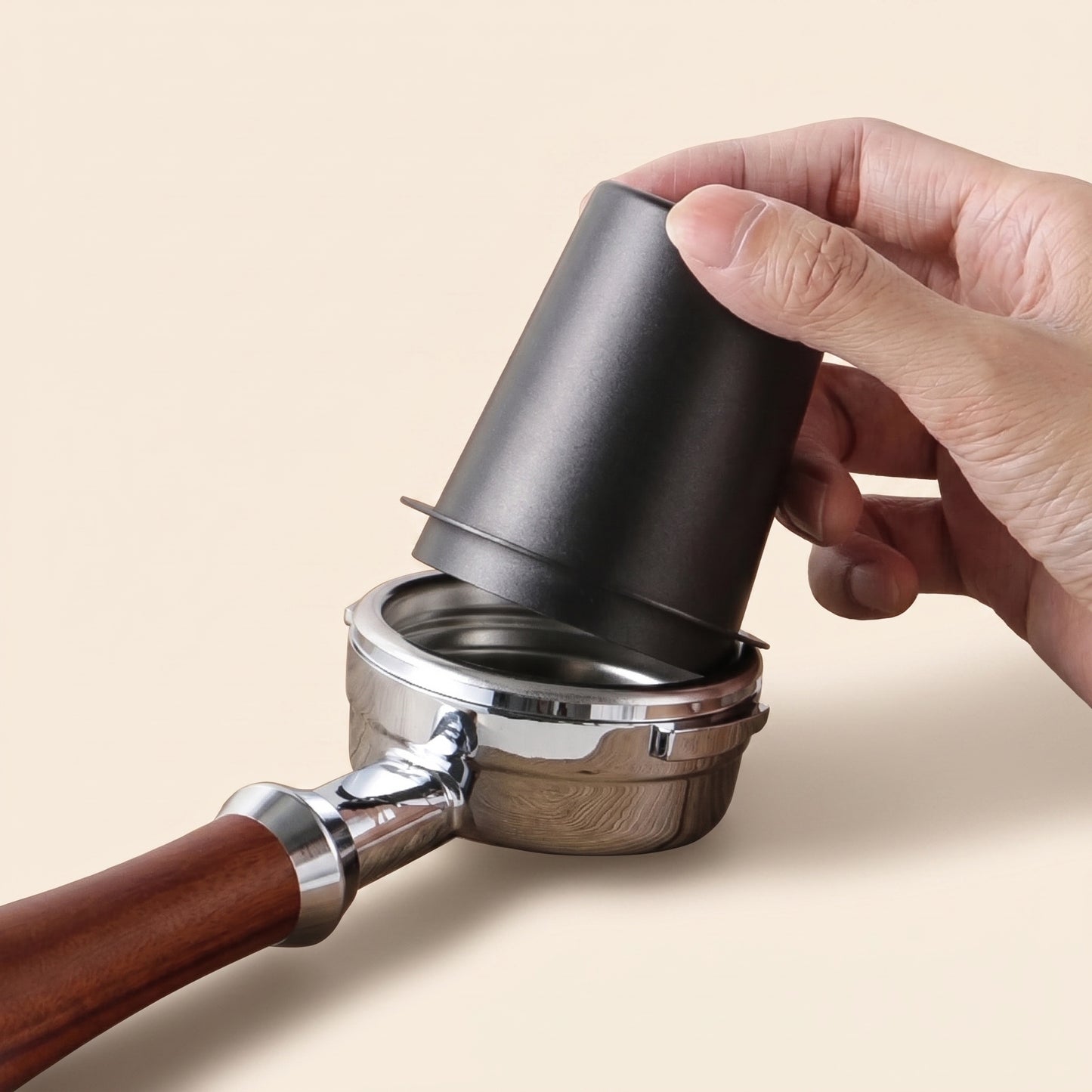 Dosing cup resting over a portafilter basket while ground coffee is added