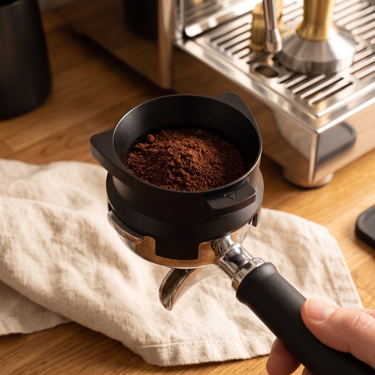 Overhead view of black dosing funnel over a Breville portafilter while dosing an espresso puck