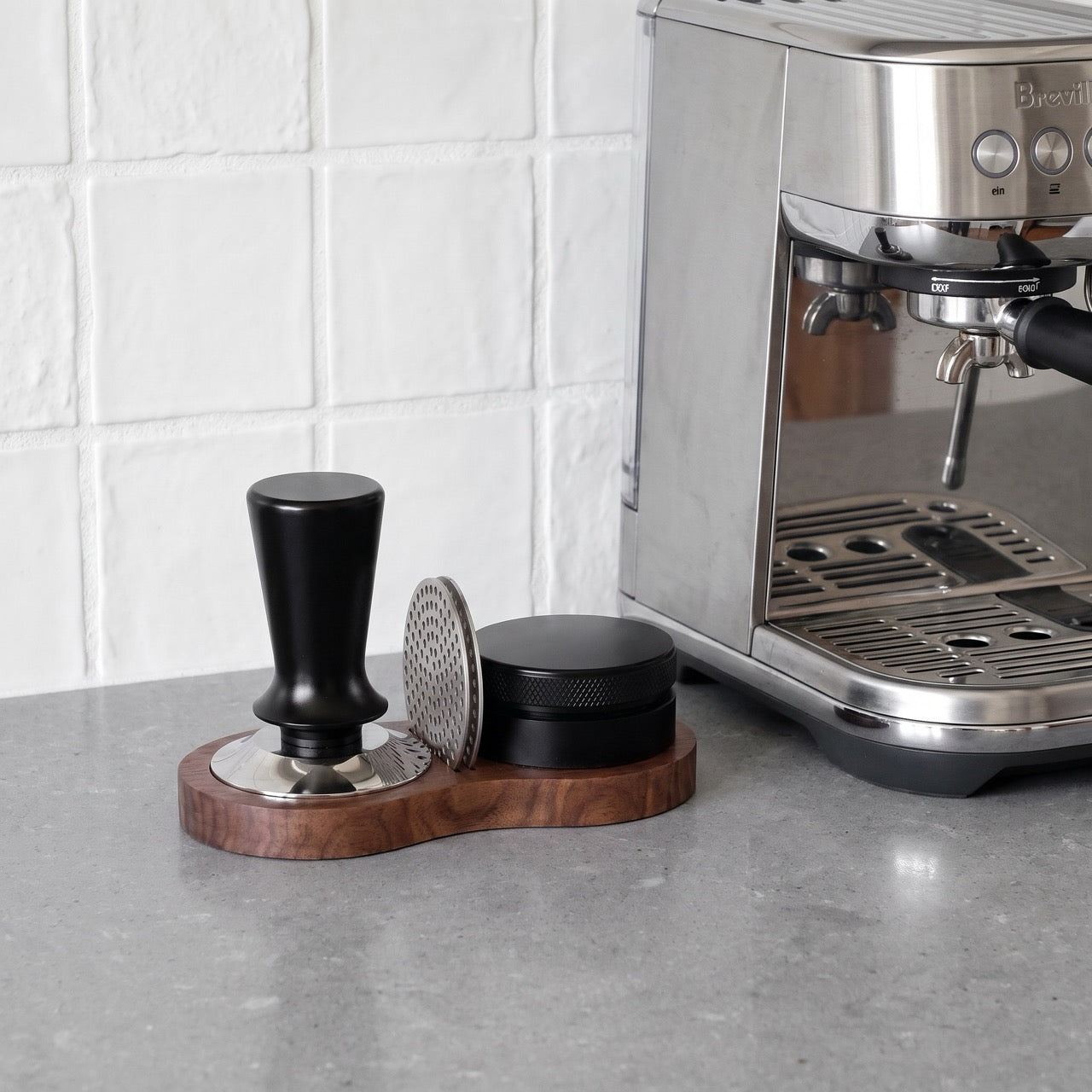 Walnut tamping station with a tamper resting upright in one of the cups