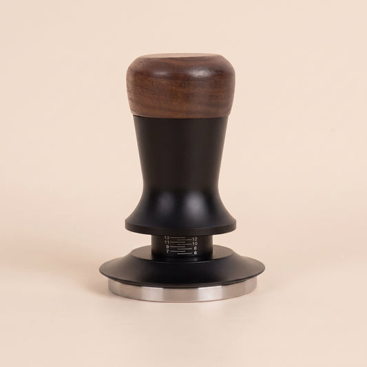 Calibrated tamper with a walnut handle, front view on a neutral background