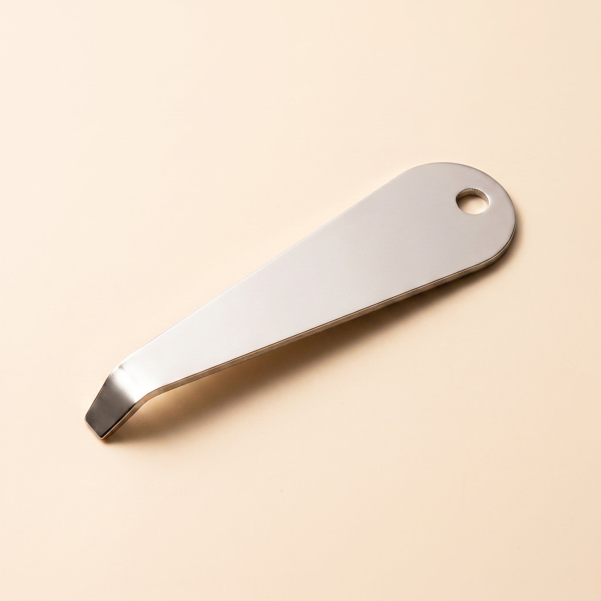 Portafilter basket removal tool profile view showing flat blade and hanging hole, polished steel