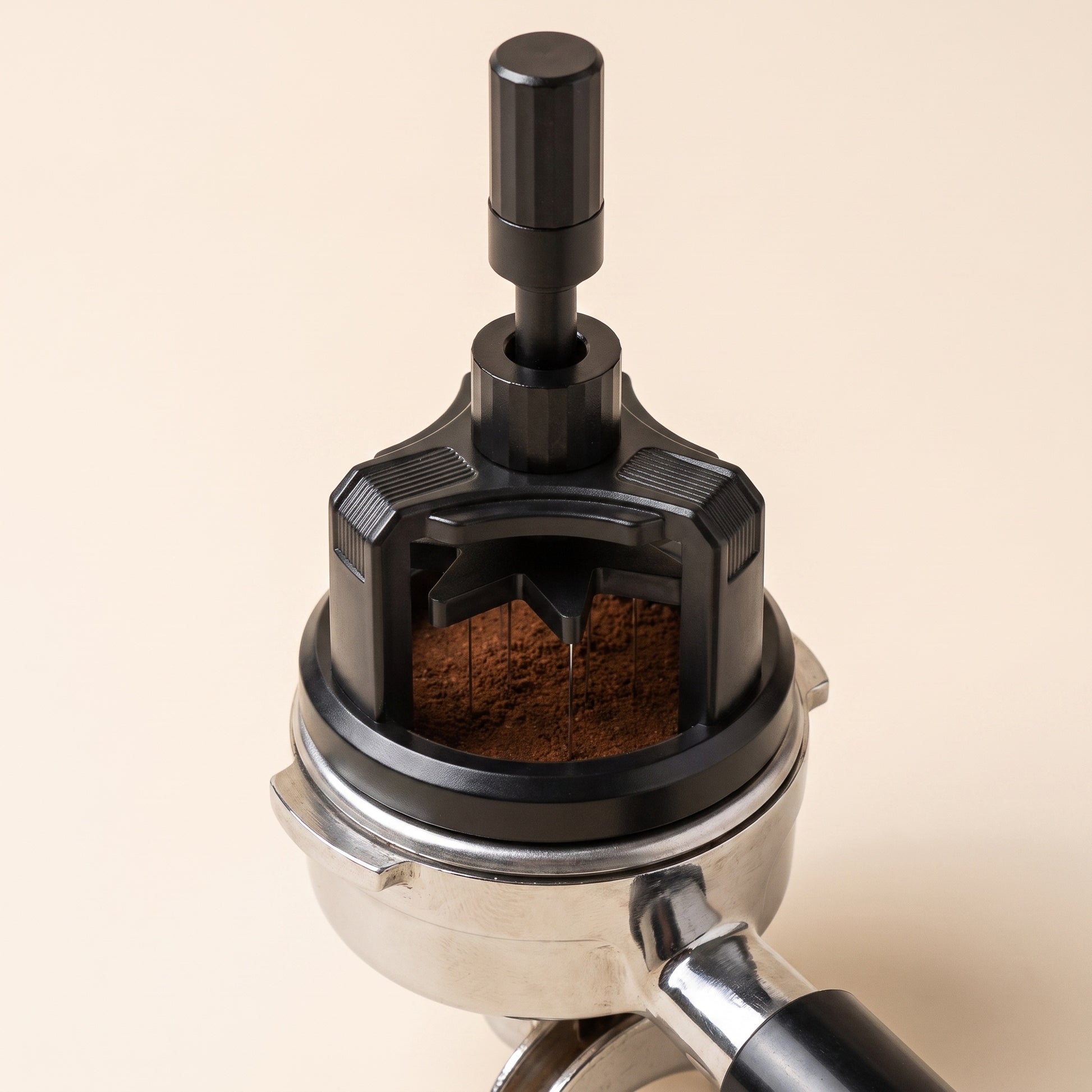 Rotary WDT tool resting on a 58mm portafilter of dosed espresso grounds, mid-twist