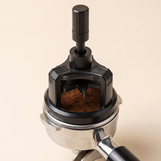 Rotary WDT tool resting on a 58mm portafilter of dosed espresso grounds, mid-twist