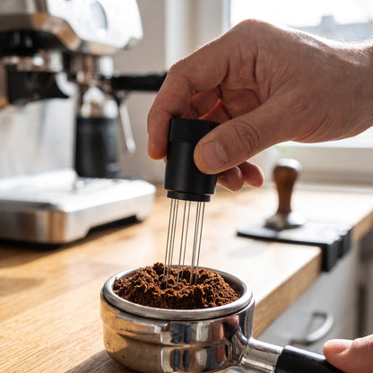 WDT tool stirring ground coffee in a portafilter basket to break up clumps before tamping